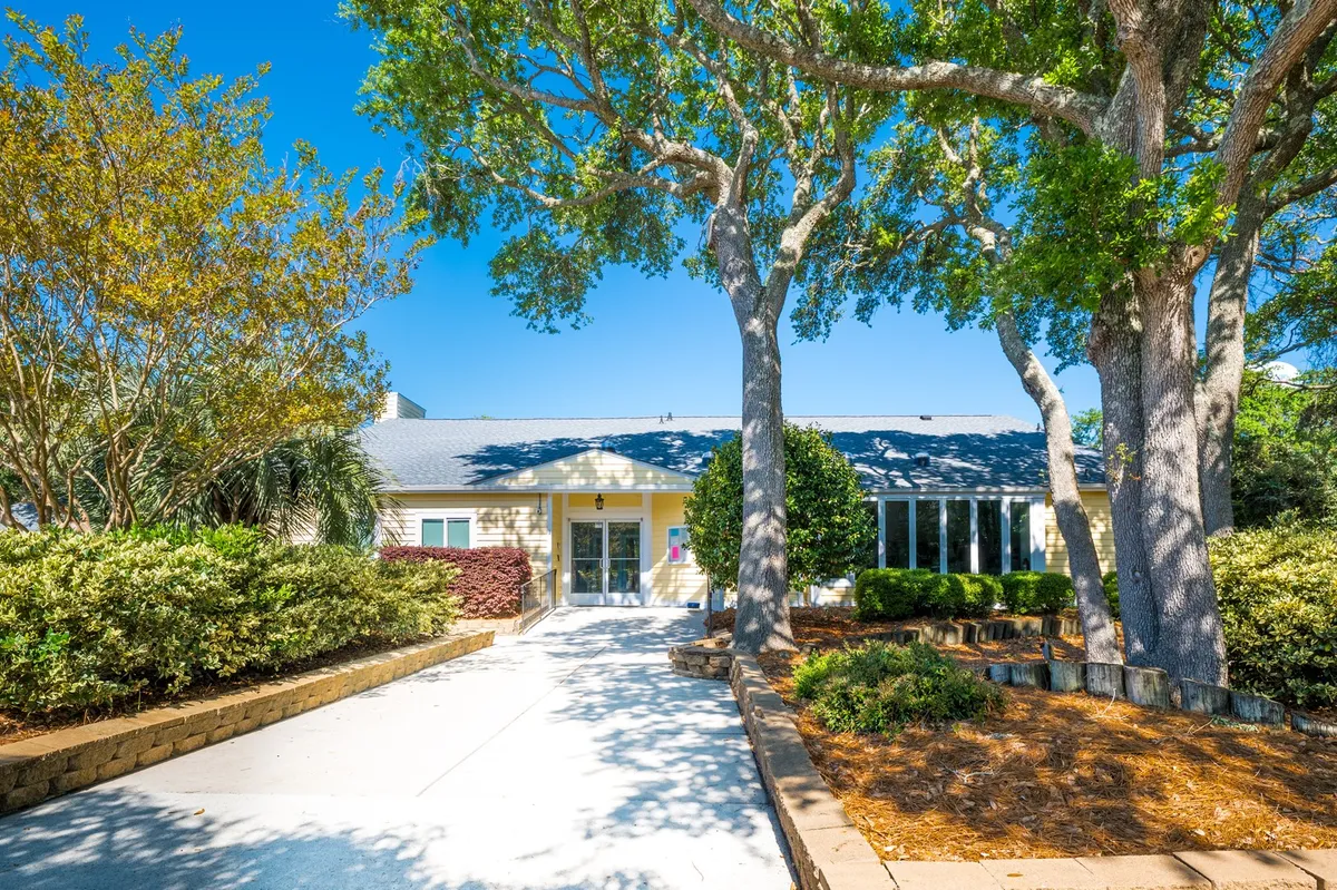 This image features the main entrance of the building, with large trees and a landscaped pathway creating a peaceful approach. The inviting entrance gives a sense of hospitality and tranquil living, while the green space hints at proximity to nature.
