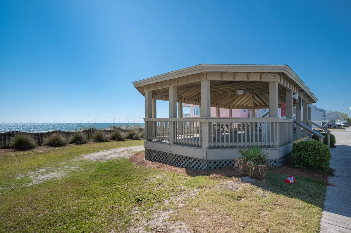 A pavilion structure with an inviting ocean view and lush surrounding greenery, creating a picturesque spot for picnics, gatherings, or simply taking in the coastal scenery. The pavilion suggests social or romantic outings and connects directly to the outdoors.