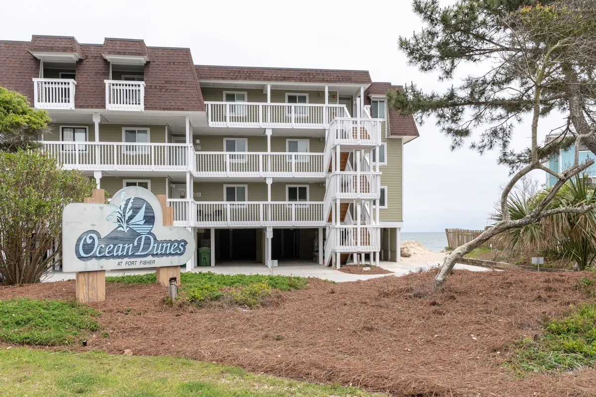 The exterior view of the Ocean Dunes property, highlighting the building’s balconies and the prominent Ocean Dunes sign. Lush greenery surrounds the area, and multiple balconies suggest opportunities for private and shared outdoor enjoyment.
